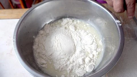 Adding flour to the base for the dough in a metal bowl Stock Photos