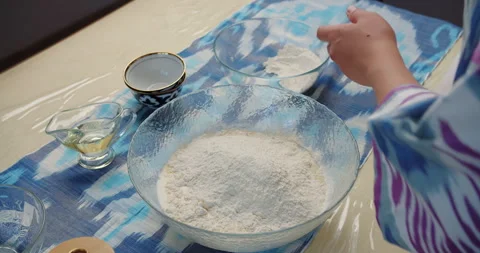 Adding flour to bowl with oil on kitchen table Stock Footage 318554848