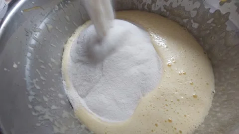Adding flour to cake batter in a metal bowl close up Stock Footage 334333031