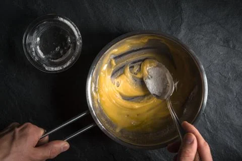 Adding flour to the melted butter on a gray table Stock Photos