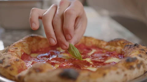 Adding Fresh Basil Leaf to Baked Pizza with Salami and Bubbly Crust Stock Footage 261890062