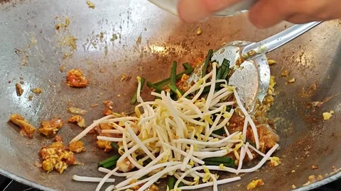 Adding fresh bean sprouts and Chinese chives to Pad Thai noodles in a wok. Vídeo Stock 339183654