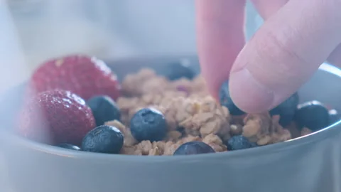 Adding fresh berries blueberry into healthy granola muesli. Healthy breakfast Видео 148691529