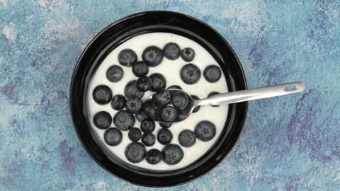 Adding fresh blueberries to yogurt bowl Видео 344363602