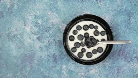 Adding fresh blueberries to yogurt bowl Видео 345172199