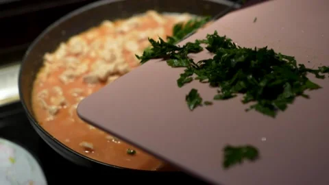 Adding fresh chopped parsley to simmering chicken meat in tomato sauce clos.. Видео 340036090