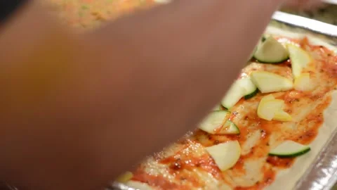 Adding Fresh Cut Zuchini onto Pizza  Stock Footage 130355150