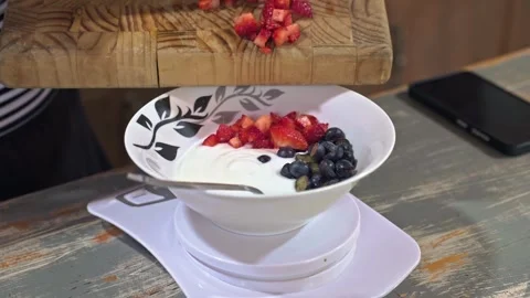 Adding Fresh Fruit to Bowl of Yogurt in Kitchen Stock Footage 321063175