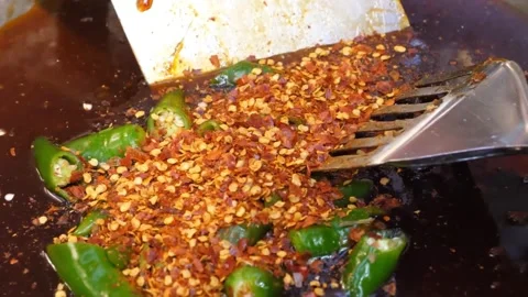 Adding Fresh Green Chilies and Dried Red Pepper Flakes to Simmering Dark Sauce, Video stock 343027598