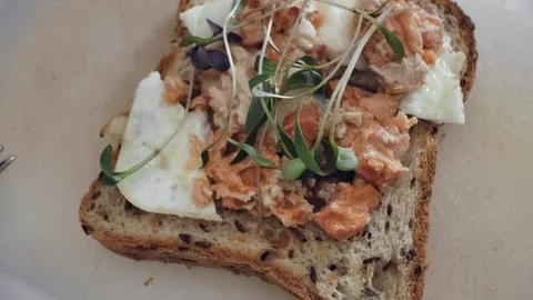 Adding fresh green sprouts on sandwich with salmon and egg Video stock 92146593