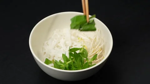 Adding Fresh Herbs and Bean Sprouts into Vietnamese Pho Bowl 库存影片 339653522
