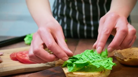 Adding a fresh leaf of lettuce on a burger in 4K. Stock Footage 153747458