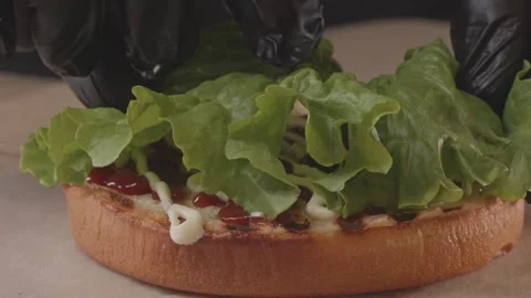 Adding fresh lettuce leaves to a burger bun. Stock Footage 312789659
