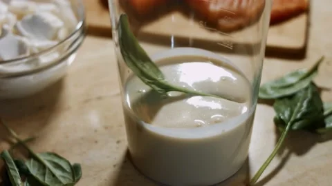 Adding fresh spinach leaves to pancake batter into a glass before mixing the Stock Footage 144902858