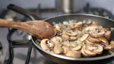 Adding fresh thyme into mushroom risotto in a frying pan. Stock Footage 134691496