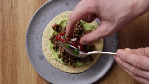 Adding Fresh Tomato Salsa to Tortilla with Guacamole and Ground Beef Top View Vidéo 336577423