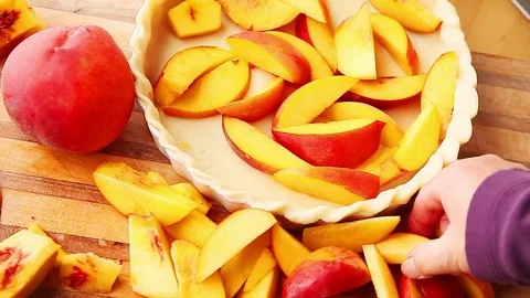 Adding freshly sliced peaches to pie crust Stock Footage 79228794