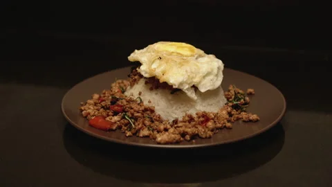 Adding fried egg on Pad Kaprao medium shot Stock Footage 150475100
