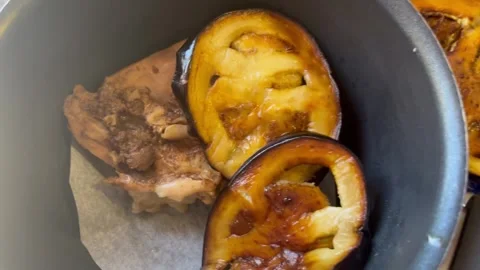 Adding Fried Eggplant Slices Over Cooked Chicken in a Pot Stock Footage 345321440