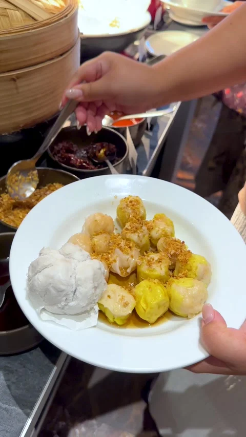 Adding Fried Garlic To Steamed Dim Sum Dumplings At A Buffet Stock Footage 334920718