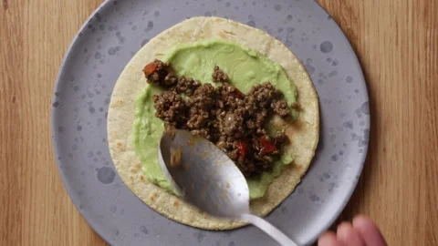 Adding Fried Ground Beef to Tortilla with Guacamole Top View Vidéo 336577762