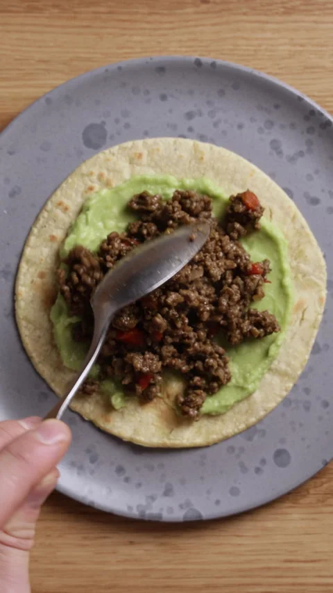 Adding Fried Ground Beef to Tortilla with Guacamole Vertical Close Up Видео 336577817