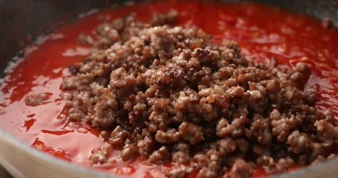Adding fried minced meat to tomato sauce in a pan. Stock Footage 249663538