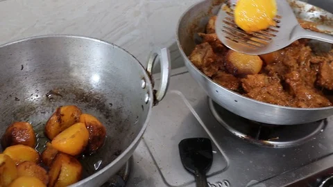 Adding fried potato to cooked chicken for making chicken gravy during biryani Stock Footage 127552699