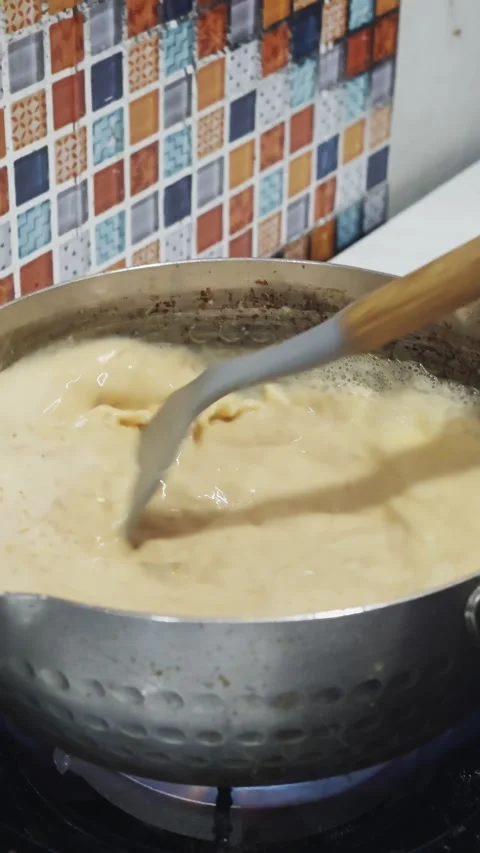 Adding Fried Tofu to Bubbling Coconut Milk Soup on a Gas Stove Video stock 329145027