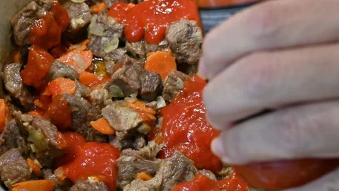 Adding fried tomato to meat, carrot, onion and garlic Stock Footage 221355968