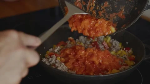 Adding fried tomatoes to minced meat and peppers in skillet Stock Footage 315243722