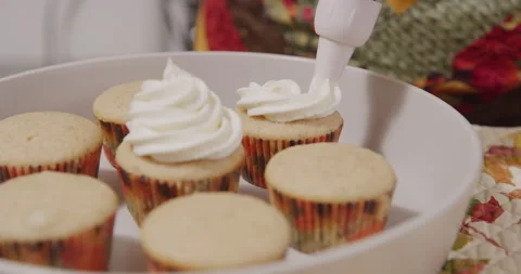 Adding frosting to second cupcake with syringe piping tool decorator Stock Footage 249371260