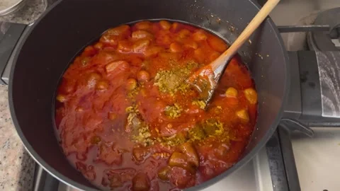 Adding Garlic and Spices to Jordanian Bamieh Stew Stock Footage 344782162