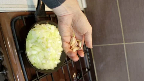 Adding garlic to fried onions in a frying pan, vertical video Stock Footage 169728049