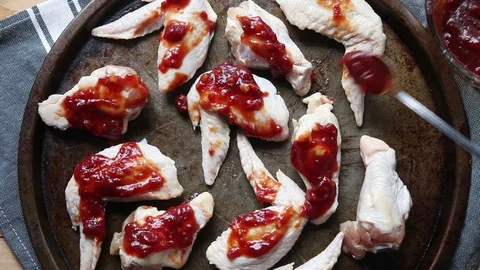 Adding a garlic ketchup based sauce to chicken wings Stock Footage 104781324