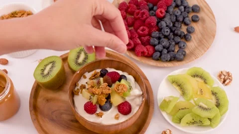 Adding Granola and Nuts to a Healthy Yogurt Fruit Bowl Stock Footage 337691161