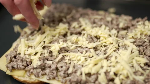 Adding grated cheese on bread rolls in slow motion. Stock Footage 135464016