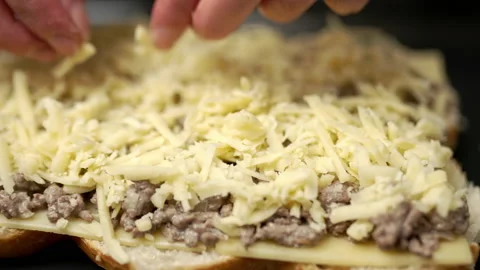 Adding grated cheese on bread rolls in slow motion. Stock Footage 135464121