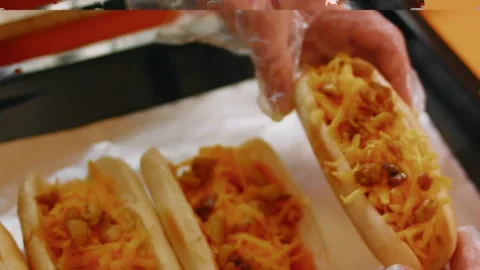 Adding grated cheese over sausage-filled bread rolls, 4K Stock Footage 341122059