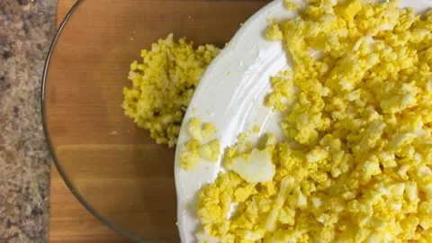 Adding grated chicken eggs to a glass bowl to prepare the snack. Stock-Footage 301323323