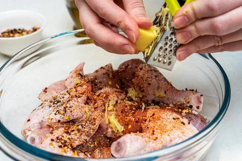 Adding grated ginger to the marinade. Marinating chicken. Stock Photos