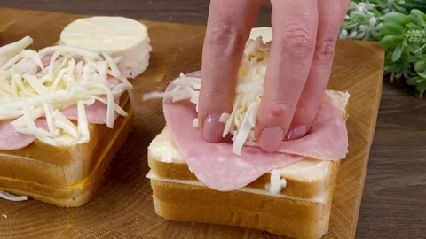 Adding grated mozzarella cheese on ham slices in hollow bread sandwich in kitche Stock Footage 324943333
