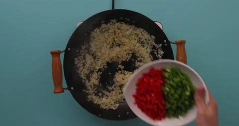 Adding green and red peppers to a skillet Stock Footage 132198539