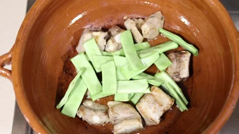 Adding green beans to a ceramic casserole. Rice preparation Stock Footage 163706993