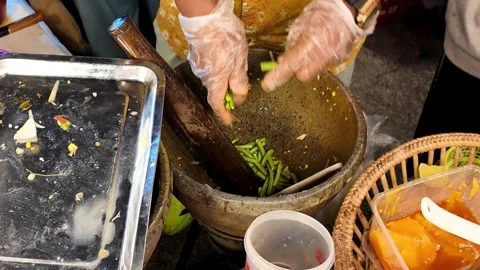 Adding green long beans to mortar for Som Tum Vidéo 347149548