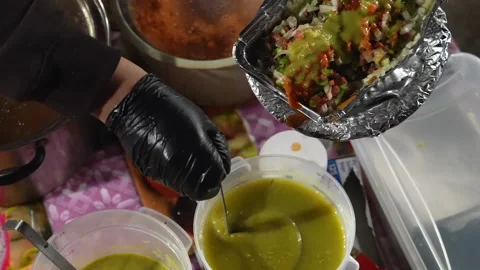 Adding Green Sauce to Papa Loca Held by Street Food Vendor Video stock 328923580