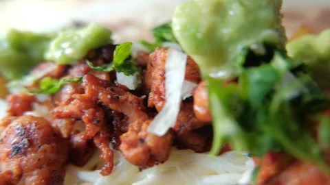 Adding green sauce on top of spicy meat, refried beans and cheese Stock Footage 147720913
