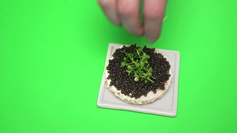 Adding greens on top of freshly made Caviar sandwich on a green background in 4K Video stock 149609716