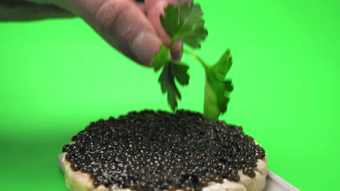 Adding greens on top of freshly made Caviar sandwich on a green background in 4K Video stock 149615096