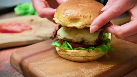 Adding half toasted bread bun on a beef steak with cheese on top of a burger. Stock Footage 153751188
